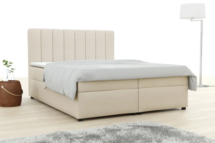 Elegantes Boxspringbett in Beige mit vertikal gestepptem Kopfteil in heller Raumatmosphäre.