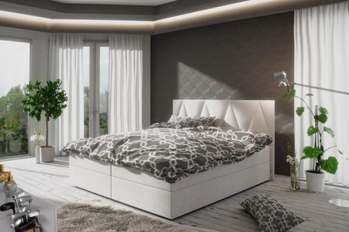 Modernes Boxspringbett in Weiß mit dekorativem Kopfteil in einem hellen Schlafzimmer.