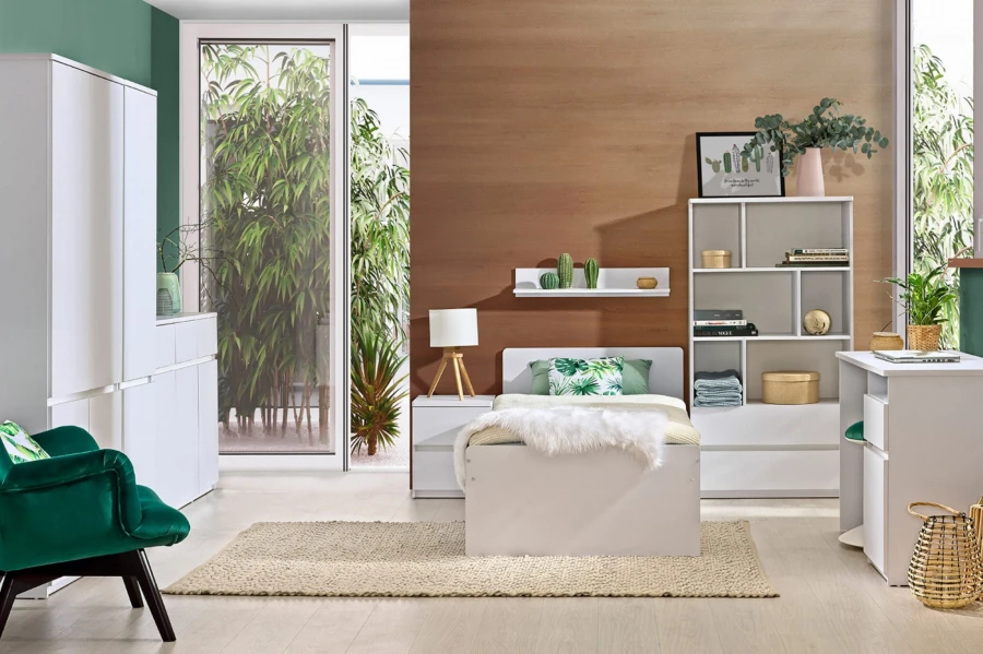 Helles Jugendzimmer mit weißem Bett, Regal und grünem Samtsessel in natürlichem Design.