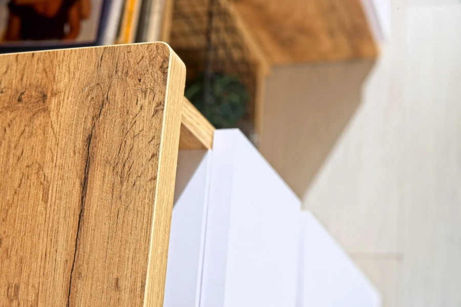 Detail der Holzmaserung einer Schreibtischplatte mit weißem Schubladenelement.