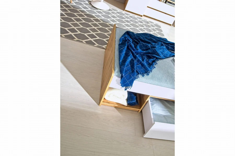 Sitzbank mit Stauraum und blauer Decke, ergänzt durch einen gemusterten Teppich im Hintergrund.