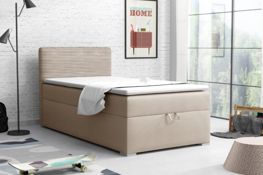 Beiges Boxspringbett mit gepolstertem Kopfteil in einem modernen Zimmer mit weißer Backsteinwand.