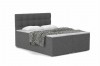 Graues Boxspringbett mit gestepptem Kopfteil und schwarz-weißer Decke.