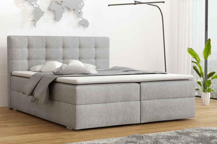 Modernes Boxspringbett in Grau mit gestepptem Kopfteil in hellem Schlafzimmer.