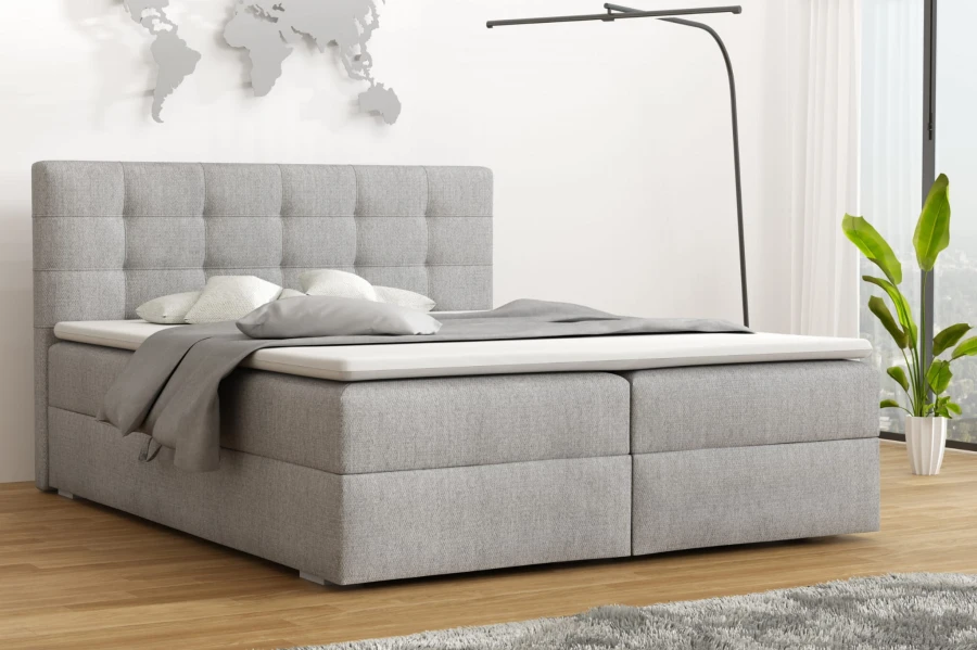 Modernes Boxspringbett in Grau mit gestepptem Kopfteil in hellem Schlafzimmer.