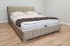 Modern beige upholstered bed with vertically quilted headboard in a bright bedroom.