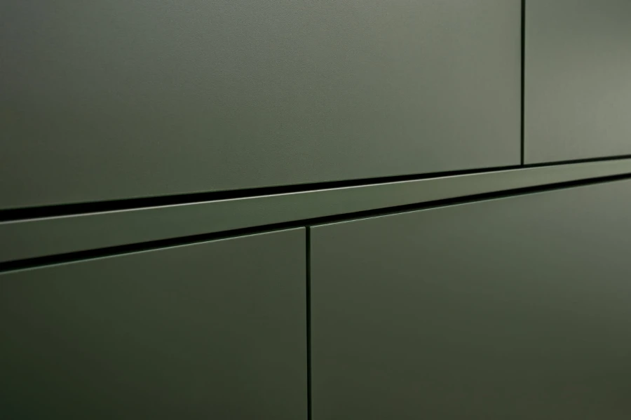 Nahaufnahme einer olivgrünen Möbelfront mit minimalistischem Design.