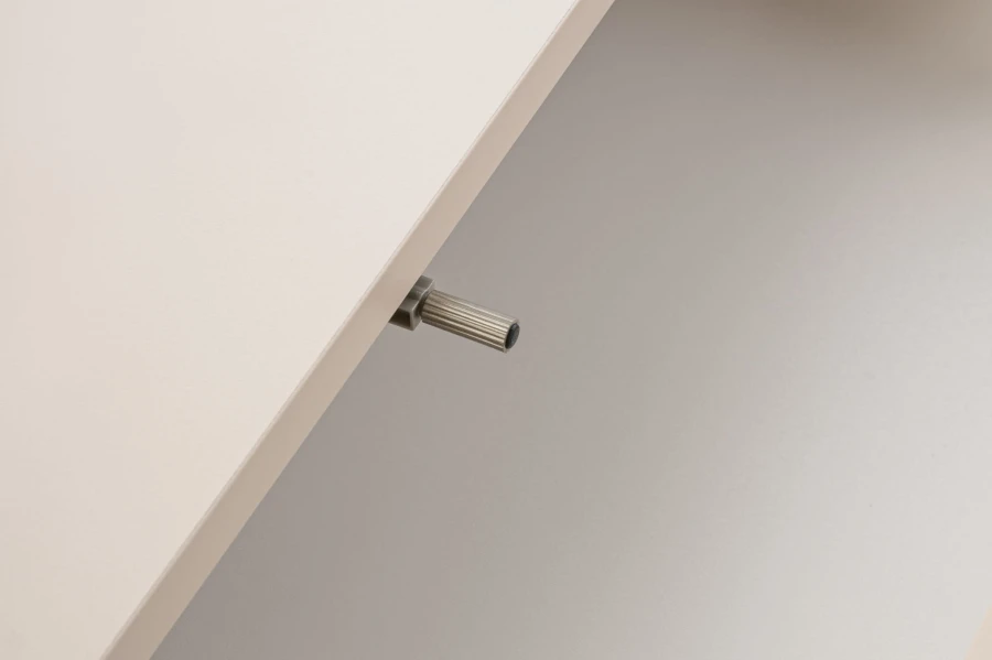 Nahaufnahme des Push-to-Open Mechanismus für grifflose Schubladen bei modernen Möbeln.