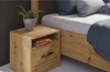 Moderner Nachttisch in Eiche-Optik mit Schublade und Pflanze im Schlafzimmer.
