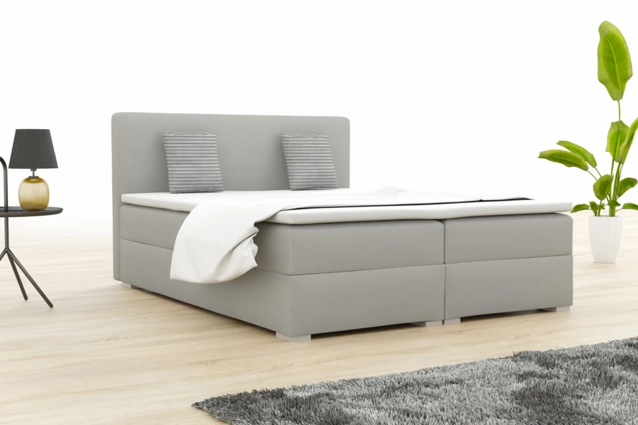 Light grey boxspring bed in a modern bedroom with a plant.