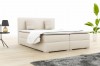 Beige boxspring bed with headboard and cushions in a light look.