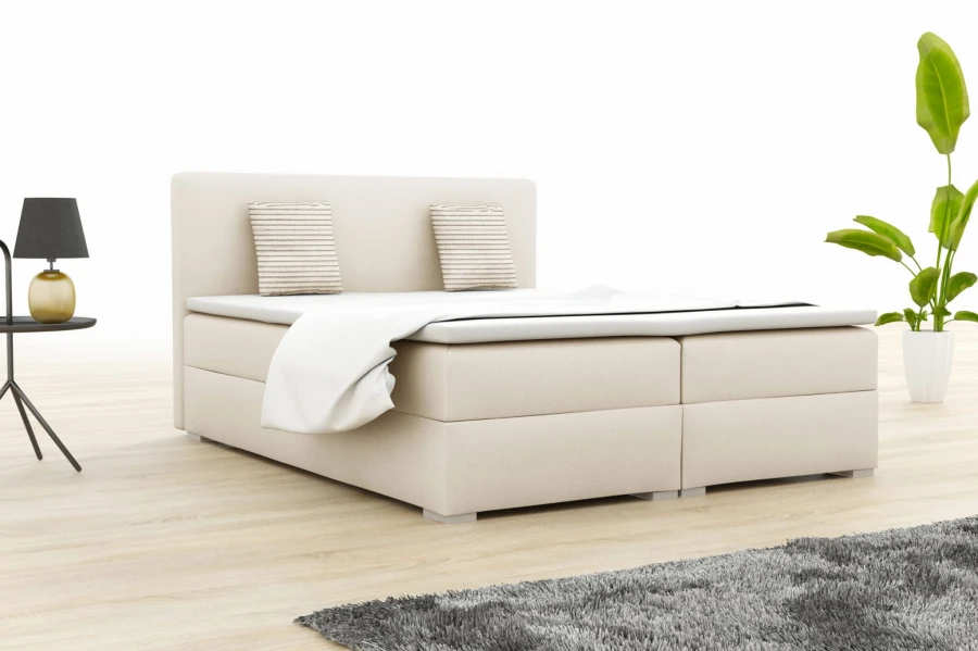 Beige boxspring bed with headboard and cushions in a light look.