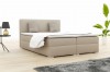 Beige boxspringbed in de slaapkamer met moderne inrichting en plant.