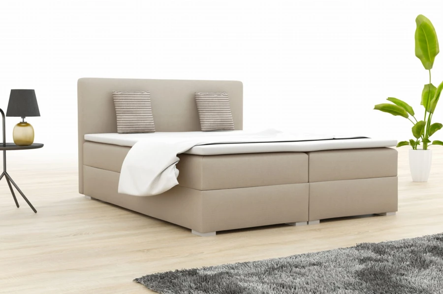 Beige boxspringbed in de slaapkamer met moderne inrichting en plant.