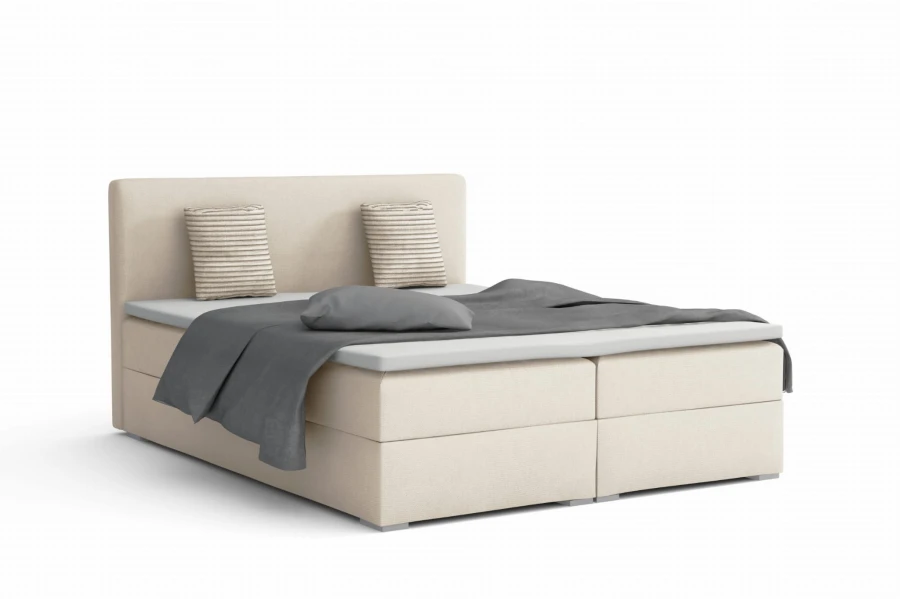 Cream-coloured boxspring bed with grey cushions and an elegant look.