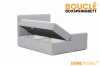 Bouclé Boxspringbett in Grau mit geöffnetem Bettkasten für praktischen Stauraum.
