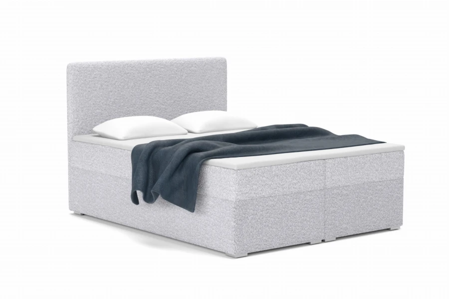 Modernes Boxspringbett mit hellgrauem Bouclé-Stoffbezug, Kissen und blauer Bettdecke.