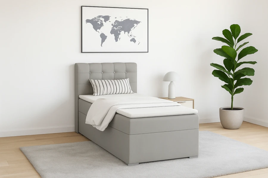 Modern eingerichtetes Schlafzimmer mit grauem Boxspringbett, Zimmerpflanze und Teppich.