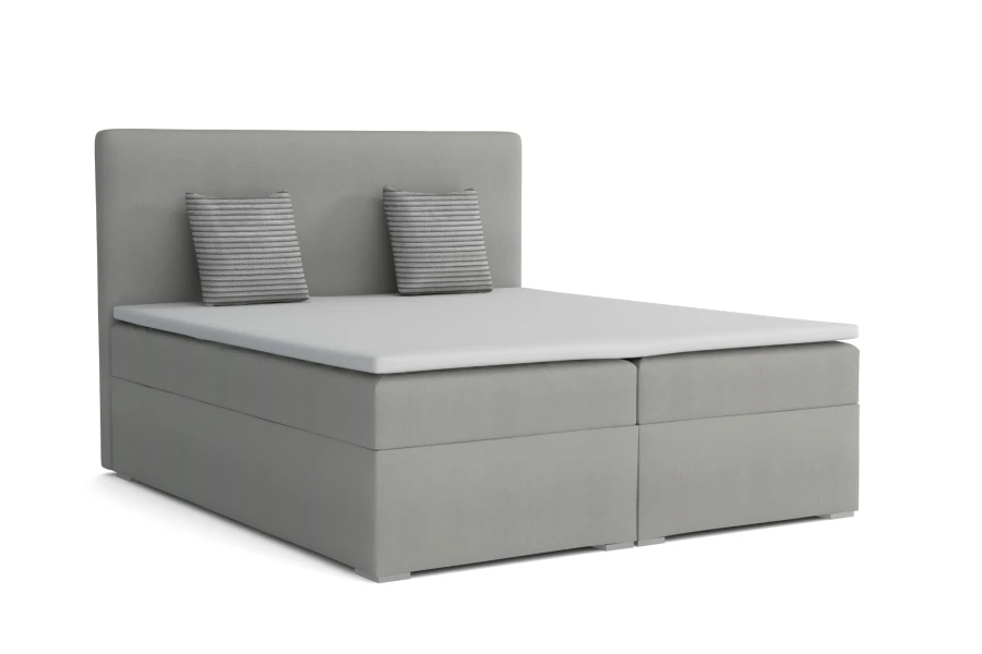 Hellgraues Boxspringbett mit zwei gestreiften Zierkissen auf weißem Hintergrund.