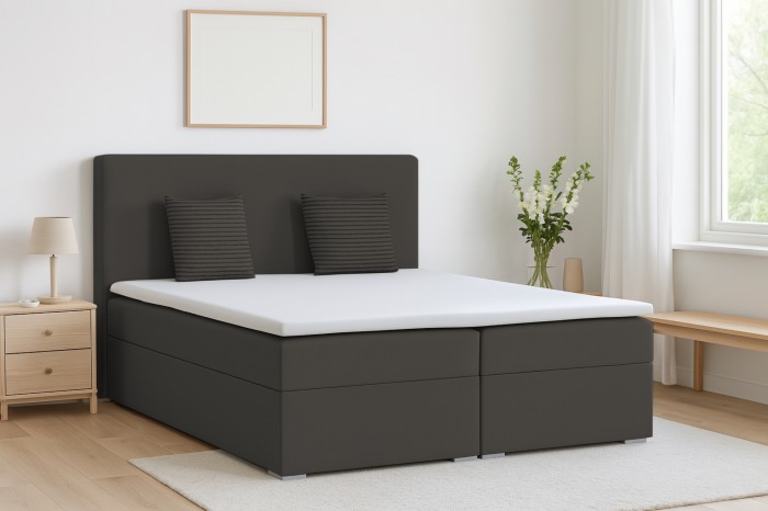 Modernes Boxspringbett in Anthrazit mit Kopfteil in einem hellen Schlafzimmer.