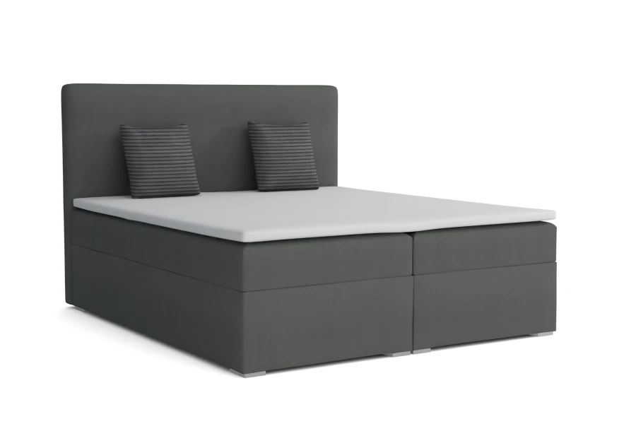 Anthrazitfarbenes Boxspringbett mit weißem Topper und Dekokissen freigestellt auf weiß.