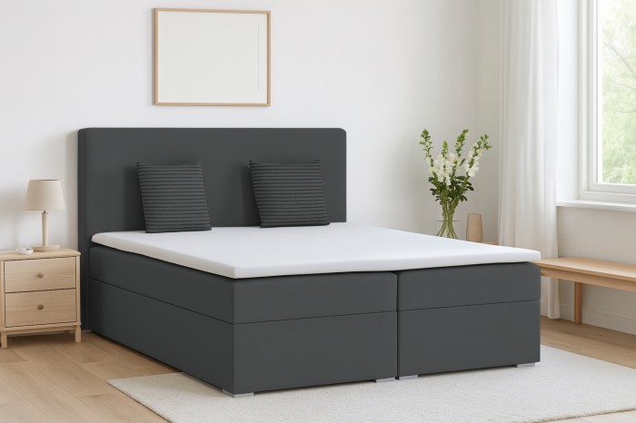 Modernes anthrazitfarbenes Boxspringbett mit weißem Topper in einer hellen Schlafzimmer-Einrichtung.