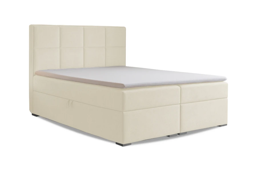 Cremefarbenes Boxspringbett mit gestepptem Kopfteil und Topper vor weißem Hintergrund