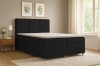 Gemütliches Schlafzimmer mit einem modernen anthrazitfarbenen Boxspringbett und Holzmöbeln.