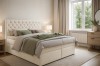 Elegantes Boxspringbett in Beige mit kristallbesetztem Kopfteil in einer gemütlichen Schlafzimmerumgebung.