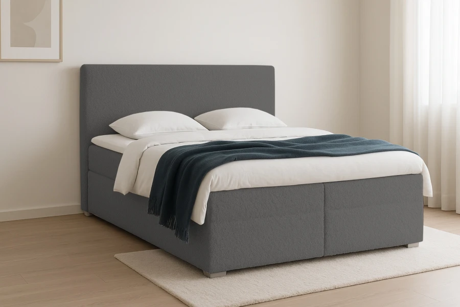 Graues Boxspringbett mit Bouclé-Stoff und blauer Tagesdecke in hellem Schlafzimmer.