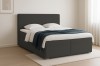 Dunkelgraues Bouclé Boxspringbett mit gemütlicher Decke und minimalistischem Design.