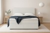Weißes Boxspringbett aus Bouclé-Stoff für ein helles, minimalistisches Schlafzimmer-Ambiente.