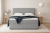 Modernes Boxspringbett in Grau aus strukturiertem Bouclé-Stoff für ein gemütliches Schlafzimmer.