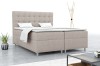 Eingerichtetes Schlafzimmer mit beigem Boxspringbett und Dekoration.