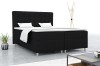 Schwarzes Boxspringbett in stilvollem Schlafzimmer-Ambiente mit Lampe und Zimmerpflanze.