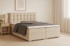 Stilvolles Boxspringbett Carly in hellem Beige mit Nachttisch und moderner Wanddekoration.