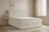 Helles Schlafzimmer mit beigem Boxspringbett, Nachttisch und modernem Teppich.