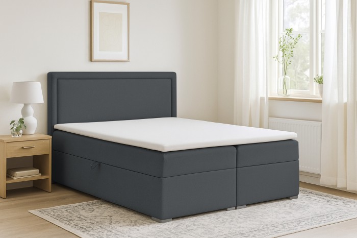 Anthrazitfarbenes Boxspringbett mit gepolstertem Kopfteil und Topper in gemütlicher Schlafzimmer-Umgebung.