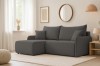 Ecksofa in Dunkelgrau in einem hell eingerichteten Wohnzimmer mit Teppich und Deko.