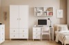 Jugendzimmer in hellen Farben mit weißem Schrank, PC-Arbeitsplatz und gemütlichem Bett.