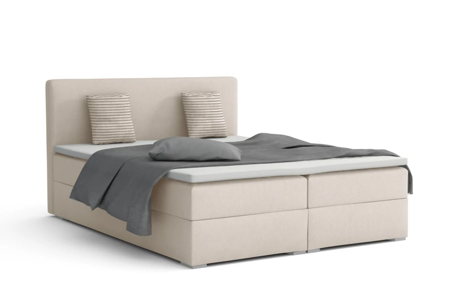 Beiges Boxspringbett mit grauer Decke und gestreiften Kissen