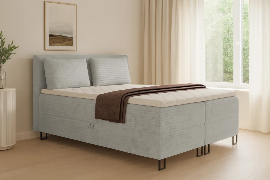 Modernes graues Boxspringbett in hellem Schlafzimmer mit Fenster und Vorhängen.