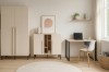 Beige Zimmereinrichtung mit Kleiderschrank, Sideboard und Schreibtisch samt weißem Stuhl auf rundem Teppich.