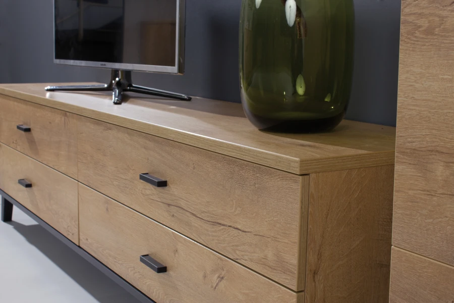 Detailaufnahme TV-Lowboard Liam: Eichenoptik mit schwarzen Griffen, dekoriert mit Vase und Fernseher.