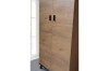 Detailansicht eines Holzschranks der Liam-Serie mit modernen schwarzen Metallgriffen.
