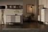 Stimmungsvolles Wohnzimmer mit beleuchtetem Sideboard, Design-Stehlampe und edlem dunklen Parkettboden.