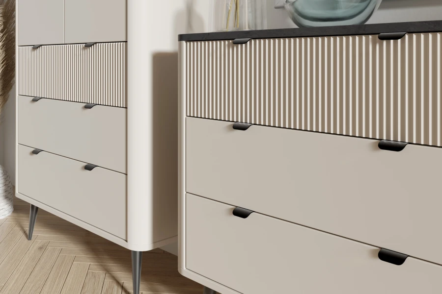Nahaufnahme moderner Kommoden in Creme mit Riffelfront-Detail und minimalistischen schwarzen Griffen.