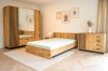 Hell gestaltetes Schlafzimmer mit LAMI Möbelset in Eiche, Wandbildern und weißem Teppich.