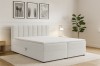 Modern wit boxspringbed Vanessa met verticaal gestikt hoofdbord in een lichte slaapkamer.