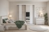 Moderne schuifdeurkast met spiegel in lichte slaapkamer met gezellig bed.